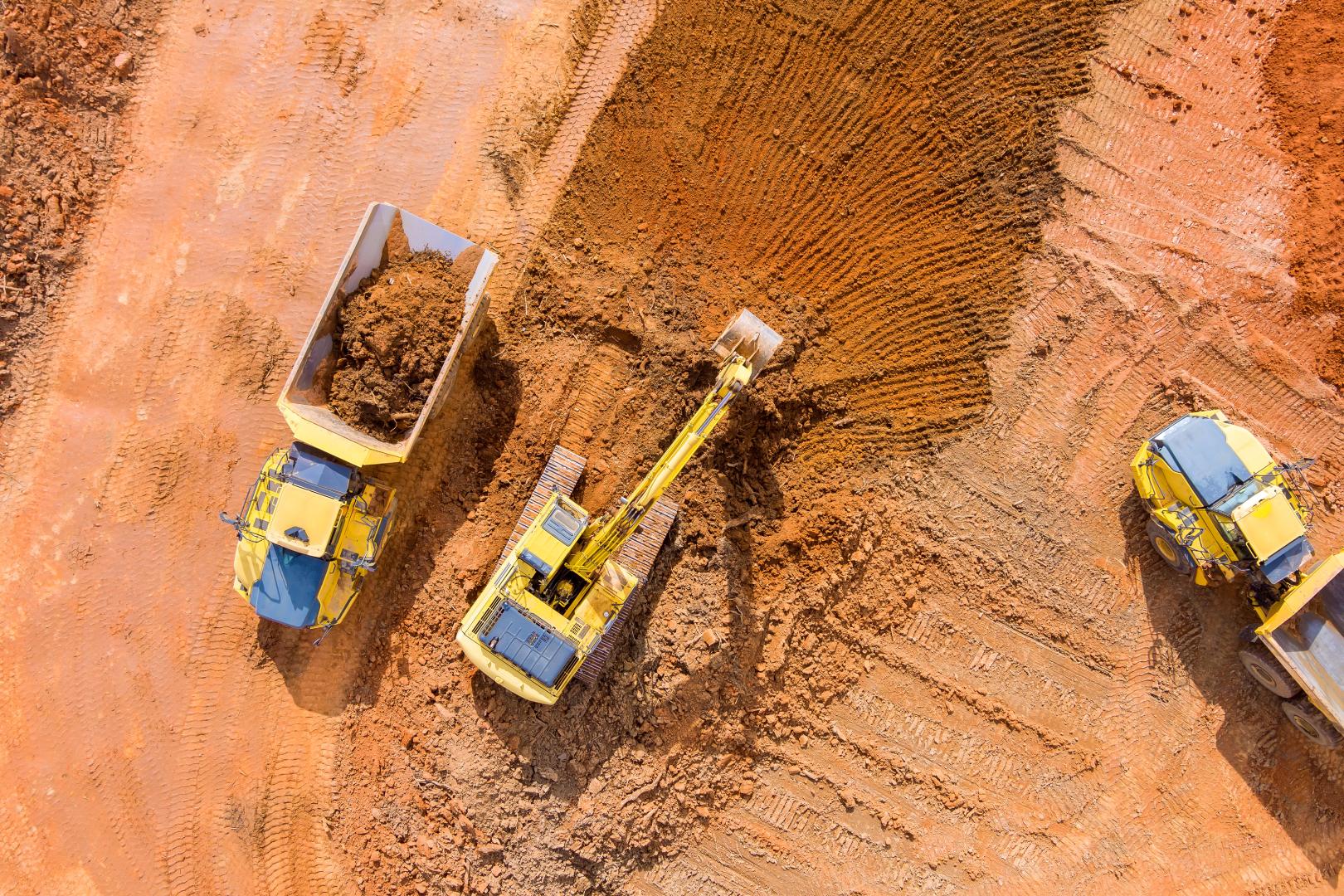 Excavator with trucks on soil