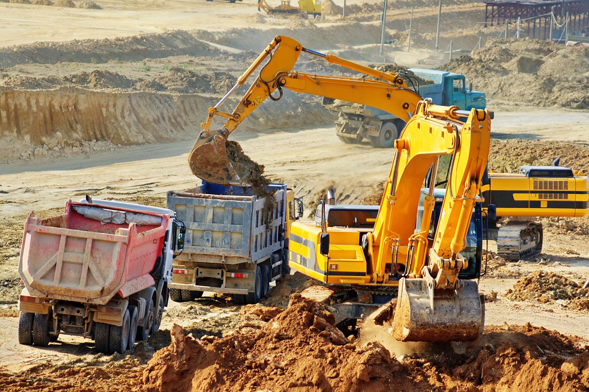 Excavator emptying soil in trucks